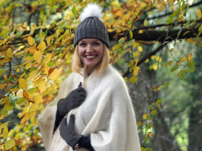 Model wearing mohair jumper and serape stood under a tree wearing woolly hat and gloves
